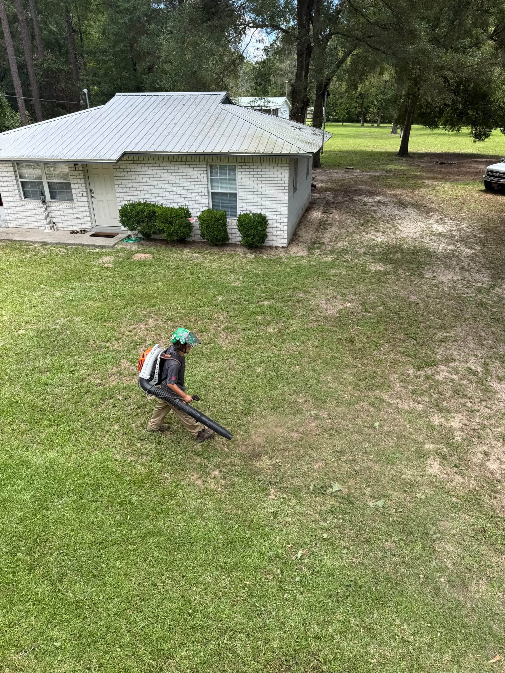 T.E.A.M. crew member blowing remaining debris from a residential lawn after tree work