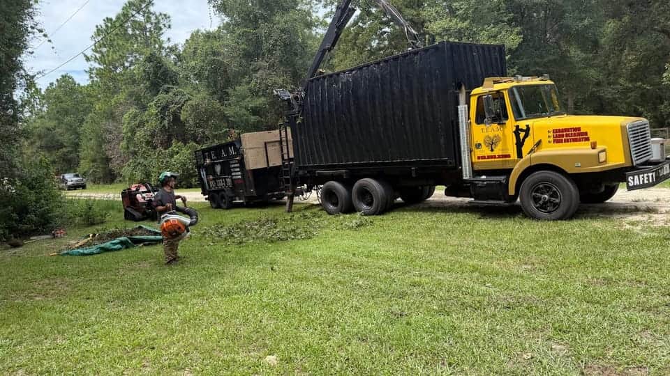 T.E.A.M. grapple truck, dump trailer, tracked loader, and cleanup crew at a residential job