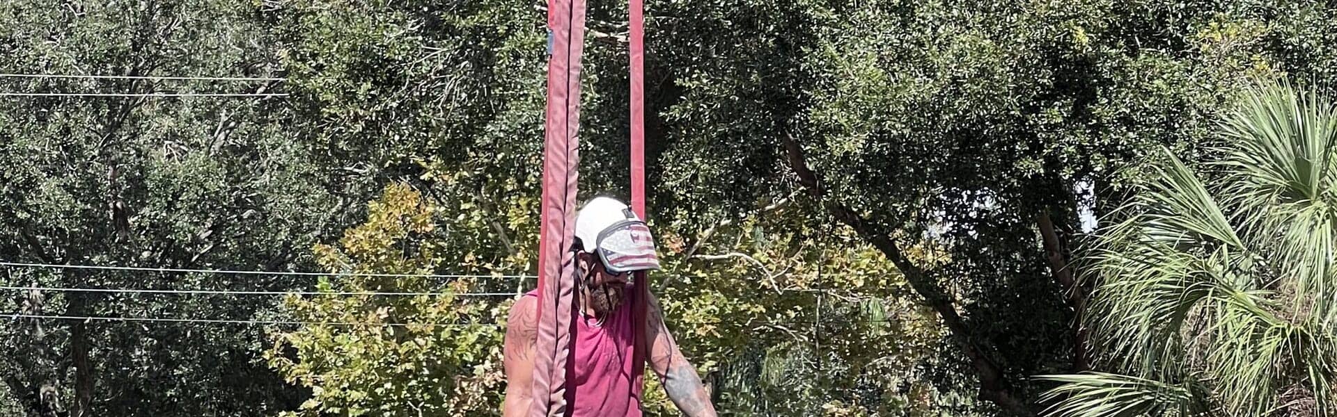 T.E.A.M. climber cutting a rigged trunk section above a Tampa roof