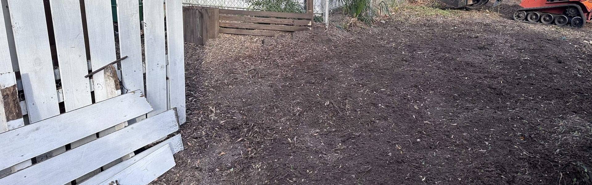 Tracked loader beside a cleared section of property after brush removal